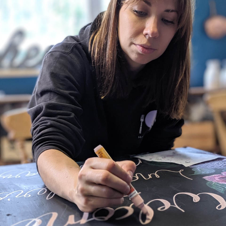 Sophie Theobald hand-lettering a chalkboard sign