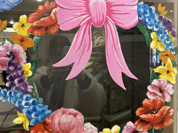 Window illustration of a pink bow surrounded by colourful flowers